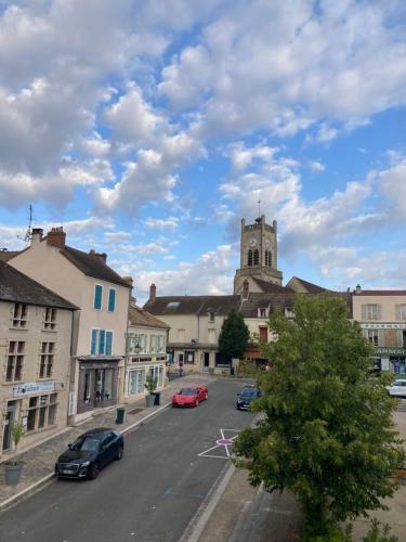 een stad met auto's geparkeerd op een parkeerplaats met een kerk bij Chambre avec 4 couchages plein cœur de village in Neauphle-le-Château