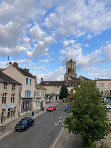 une ville avec des voitures garées dans un parking avec une église dans l'établissement Appart 6 couchages en plein cœur de village, à Neauphle-le-Château