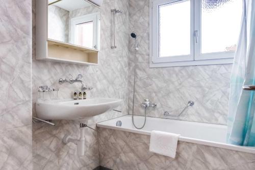 y baño con lavabo, ducha, bañera y lavamanos. en Apartment Obem Doregade - GRIWA RENT AG, en Grindelwald