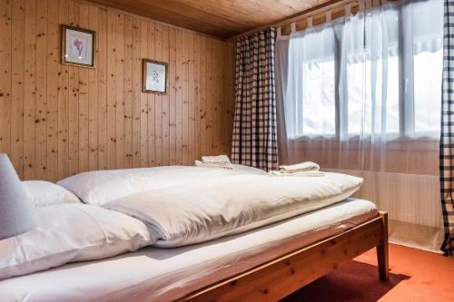 Cama en habitación con ventana en Apartment Obem Doregade - GRIWA RENT AG en Grindelwald