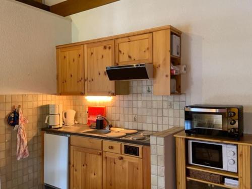 eine Küche mit Holzschränken und einer Mikrowelle in der Unterkunft Résidence A9 - Les Myosotis in Les Mosses