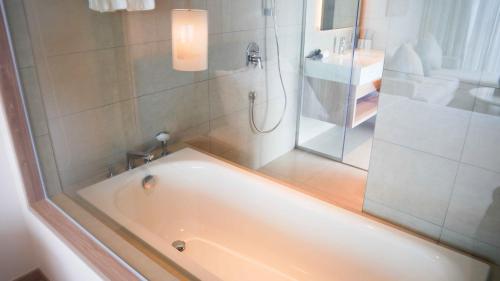La salle de bains est pourvue d'une baignoire et d'une douche avec une porte en verre. dans l'établissement View Natural Wonders A La Carte Ha Long Bay VIE, à Hạ Long