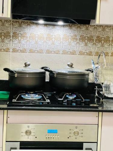 two pots on top of a stove in a kitchen at Crown Elegance Suites in Kampala