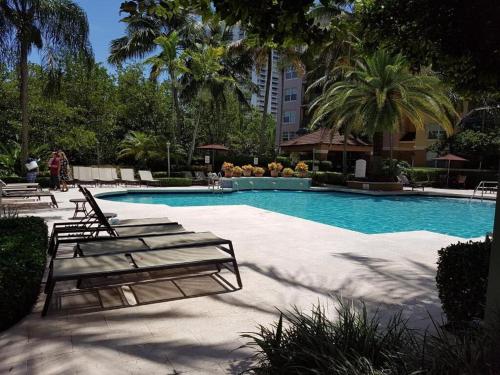 a swimming pool with lounge chairs and palm trees at Uhost AI - 3BR Condo - Stunning Water Views in Miami