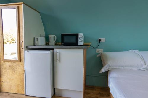 a room with a refrigerator and a bed with a microwave at Broom Leisure Camping Pods in Annan