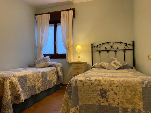 a bedroom with two beds and a window at Apartamentos Rurales La Bardenilla in Panes