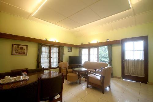 sala de estar con mesa, sillas y TV en Hotel Villa Rawa Pening Pratama by Aparian, en Bandungan