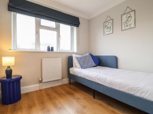 a bedroom with a blue bed and a window at Herring House in Lowestoft