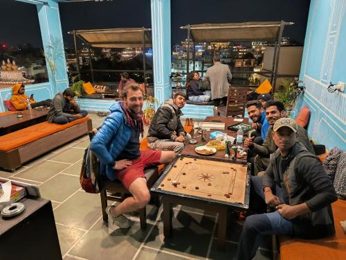a group of people sitting around a table playing a video game at Madpackers Udaipur in Udaipur