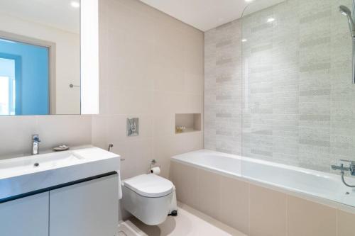 een badkamer met een bad, een toilet en een wastafel bij Silkhaus palm view 1BDR with private beach in Emaar Beachfront in Dubai