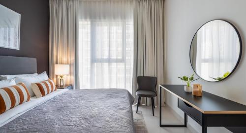 een slaapkamer met een bed, een bureau en een spiegel bij Silkhaus palm view 1BDR with private beach in Emaar Beachfront in Dubai