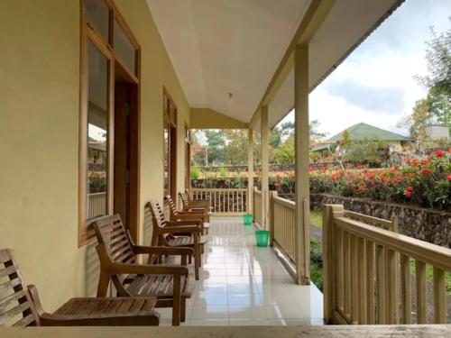 a row of chairs on a porch with flowers at Lembah Rinjani Villa & Resto by ecommerceloka in Sembalun Lawang