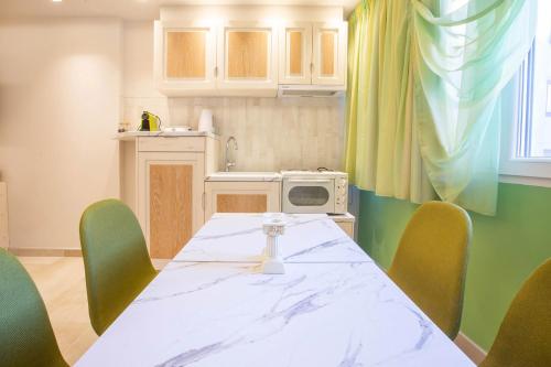 a kitchen with a table with green chairs and a white counter top at Mariet Athens Boutique Spa in Athens