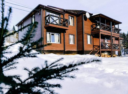 a log cabin in the snow with a tree at Приватна садиба Два сини та донька in Bukovel