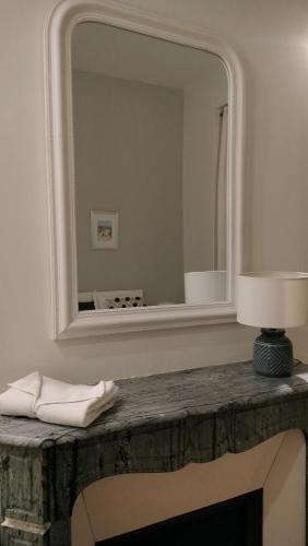 un miroir au-dessus d'une table avec une lampe dans l'établissement Appartement F3 au balcon de la Place du Martroi, à Orléans