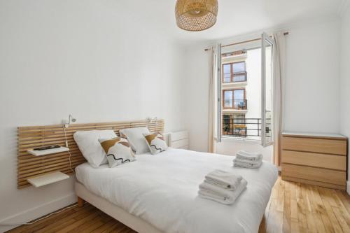 een witte slaapkamer met een groot bed en een raam bij 667 Suite Clement - Apartment near Paris in Vincennes