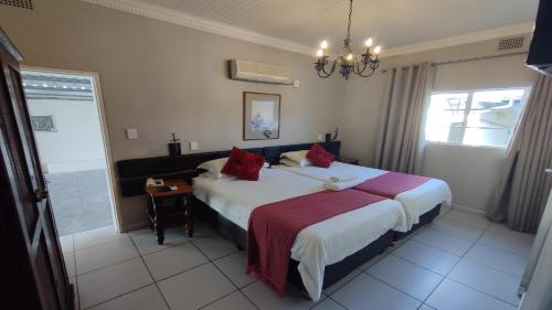 a hotel room with a bed and a chandelier at Bird's Nest Guest House in Keetmanshoop