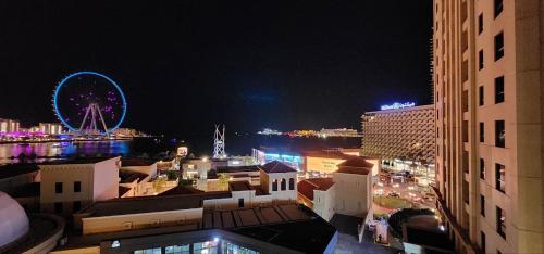 vista su una città di notte con ruota panoramica di Urban Heaven, Premium Hostel - JBR - Walk To Beach, Metro Station a Dubai