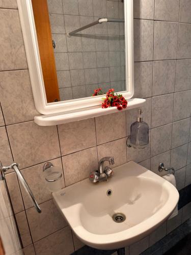 ein Waschbecken mit einem Spiegel und eine Blume auf einem Regal in der Unterkunft Luxury Beach House 2 in Xiropigado