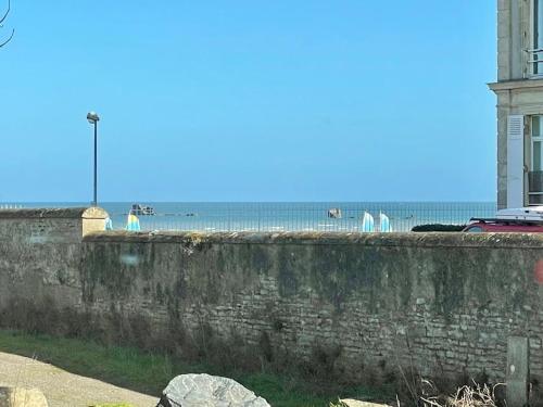 a stone wall with the beach in the background at Horizon Vert by Melrose in Asnelles