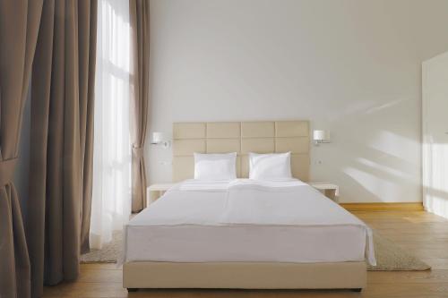 um quarto com uma cama branca com lençóis e almofadas brancos em Lanterna Rooms City Center em Novi Sad