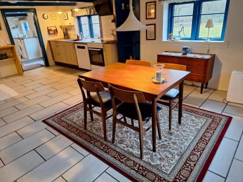 a kitchen with a wooden table and chairs on a rug at Rødsten Gæstegård in Ulfborg