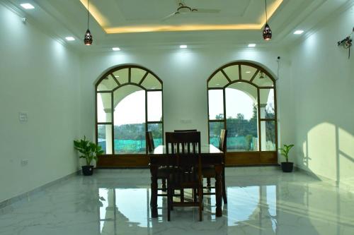 una sala da pranzo con tavolo e alcune finestre di Ranthambore jalsa a Sawai Madhopur