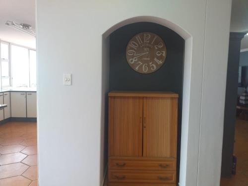 a clock on a wall next to a wooden cabinet at Rondevoux 27 in Margate