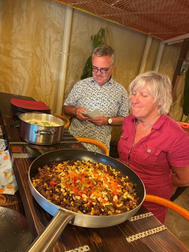 a man and a woman standing next to a pan of food at O Cupidon Doré in Saly Portudal