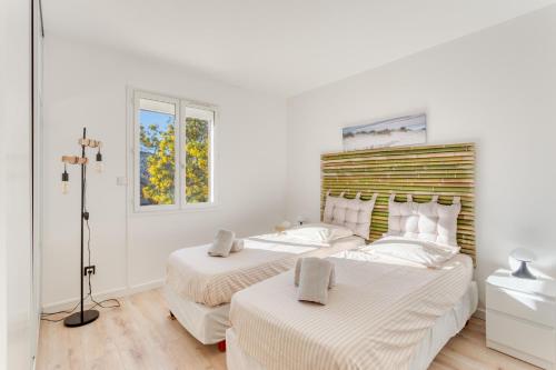two beds in a bedroom with white walls at SmartStay - Hyeres villa vue mer in Hyères