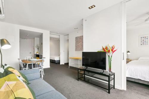 a living room with a couch and a tv and a bed at East Melb 2bed parking pet friendly in Melbourne