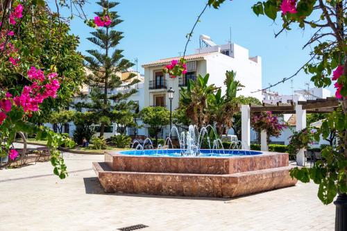 a fountain in the middle of a courtyard with pink flowers at Villa Las Palomas con piscina privada by At Home Costa del Sol in Torrox