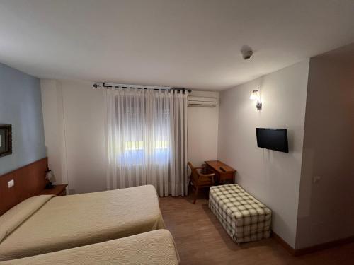 a hotel room with a bed and a chair and a television at Hotel Puente de Piedra in Zamora