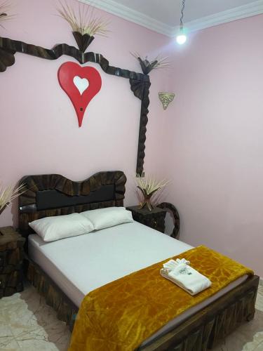 a bedroom with a bed with a heart on the wall at Dar Kernaf Eco House For Families I Entire Comfy Appartment I Fibre Internet Up to 100 Mbps I PALMS in Er Rachidia