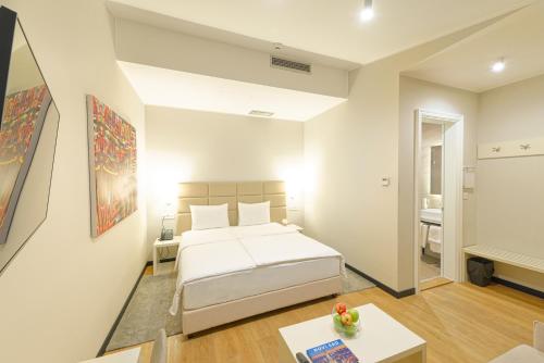 a white bedroom with a bed and a table at Lanterna Rooms City Center in Novi Sad