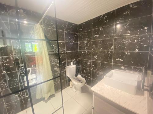 a black tiled bathroom with a toilet and a sink at Bas de Villa - Nid d’amour in Rivière-Salée