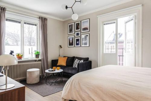 a bedroom with a bed and a couch and windows at Modern 1 Bed Gem Stylish City Apartment in Stockholm