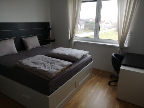 a bedroom with a bed and a desk and a window at Apartma Elton in Gornja Radgona