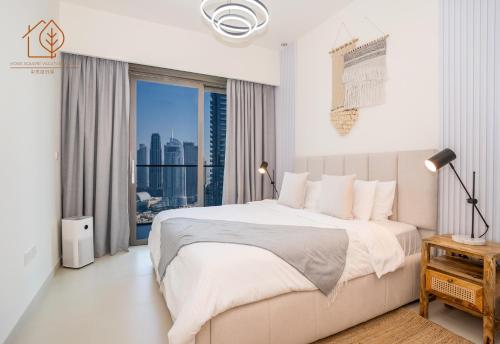 a white bedroom with a large bed and a window at Family Apartment with Burj Views at Top Floor 175BC-3 in Dubai
