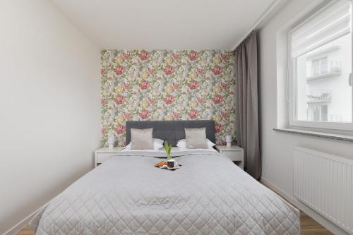 a bedroom with a large bed with a floral wallpaper at Seaside Porta Mare Apartment with Balcony Kołobrzeg by Renters in Kołobrzeg