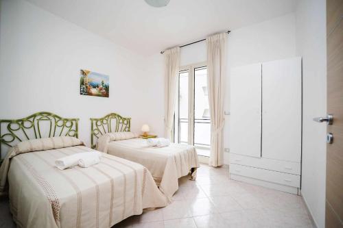 una camera da letto con due letti e una finestra di Casa di Alice By Vivimy a Gallipoli