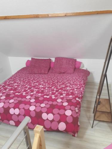 - un lit avec des draps et des oreillers en polka rose et blanc dans l'établissement appartement au calme, à Horgues