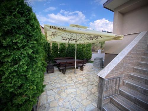 a patio with an umbrella and a wooden bench at Villa Sunrise in Sarajevo