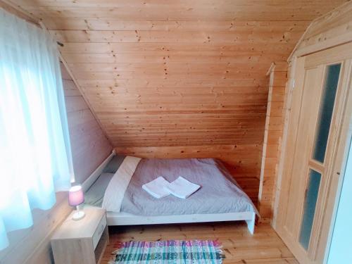 a small bed in a wooden room with a window at Domek Nad Zatoką in Giżycko