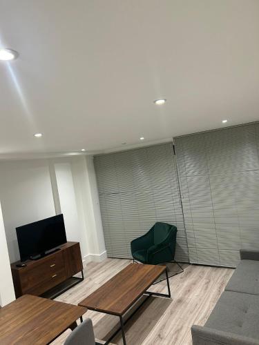 a living room with a table and a green chair at Spacious 2 Bed Ilford London in Ilford