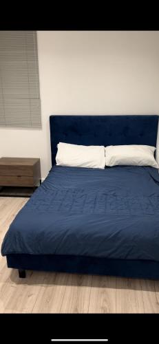 a blue bed with a white pillow on top of it at Spacious 2 Bed Ilford London in Ilford