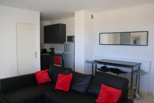 - un salon avec un canapé noir et des oreillers rouges dans l'établissement Appartement 408, Natura beach au village naturiste, au Cap d'Agde