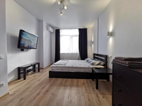 a bedroom with a bed and a tv on a wall at Green Apartments in Chernihiv
