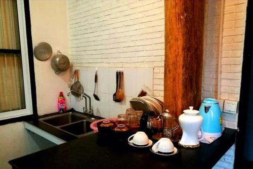 a kitchen counter top with dishes and a sink at Brightness Villa (Private Home Stay) in Phumĭ Poŭthĭ Mâ Srei