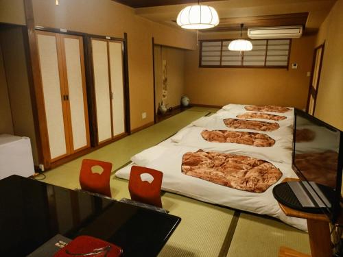 Habitación con 4 camas grandes en el suelo y sillas rojas en Hotel Edoya en Tokio